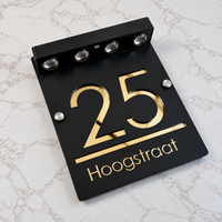 LumiSpot in Zwart / goud: zwart huisnummerbord met gouden letters en vier led-spotjes op zonne-energie