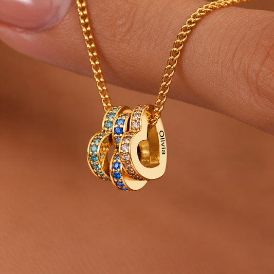Close-up van de HeartStone hartjes in goud, met de naam Olivia gegraveerd en zirkonia's in de kleur van de geboortemaand