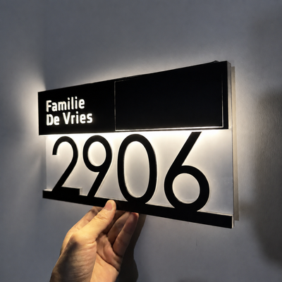LumiAdres solar LED naambord met huisnummer en straatnaam, verlicht aan de gevel in het donker