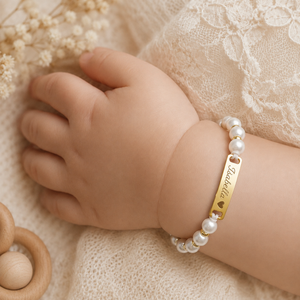 Perla naamarmband met parels om een babypolsje, goudkleurige plaat gegraveerd met de naam Isabella en een hartje