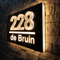 Huisnummer met verlichting in het donker en de regen: de 3D-cijfers en de naam van de LumiRelief lichten warm wit op