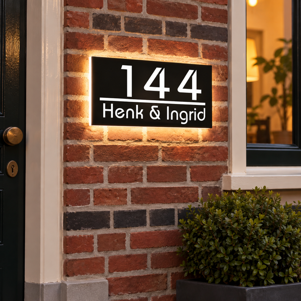 Huisnummer met verlichting en naam in het donker: LumiHalo met 144 en Henk & Ingrid op een bakstenen gevel