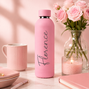 Roze RVS drinkfles met gegraveerde naam naast een boeket rozen
