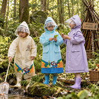 Kinderen in beige, lichtblauwe en lila RainBuddy kinderregenjas ontdekken het bos bij een beekje