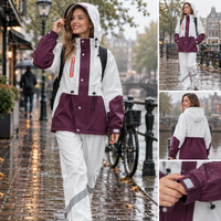 Vrouw in aubergine-wit RainShield regenpak met capuchon in de stad