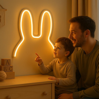 SnuffiLight witte konijn LED-lamp met warme gloed waarnaar jongetje wijst met vader in kinderkamer